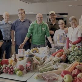 Teilnehmer:innen im Treff am See in Böblingen stehen hinter einem Tisch mit geretteten Lebensmitteln