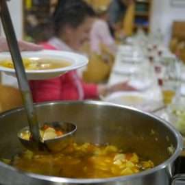 Die Teilnehmer der Schnippeldisco sitzen am gedeckten Tisch und schöpfen leckere Gemüsesuppe