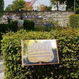 Das Ess-Gärtle - ein Schild mit Namen im Vordergrund, dahinter fleißige Gärtner