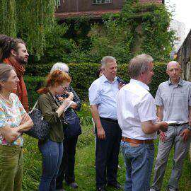 Umweltminister Franz Untersteller schaut sich interessiert einige Bilder an, die die Aktionen der Initiative Essbare Stadt Böblingen dokumentieren. Einige Aktive sowie Journalisten schauen zu